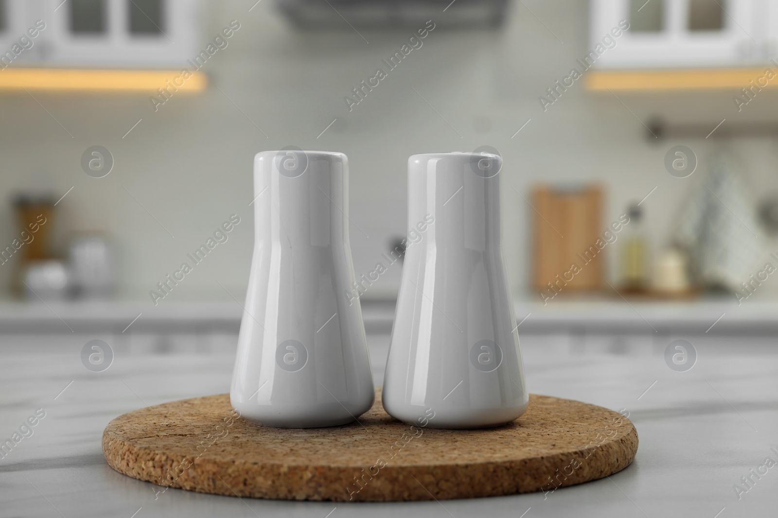 Photo of Ceramic salt and pepper shakers on white marble table in kitchen