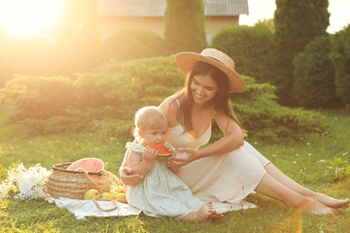 Photo of Mother with her baby daughter having picnic in garden on sunny day