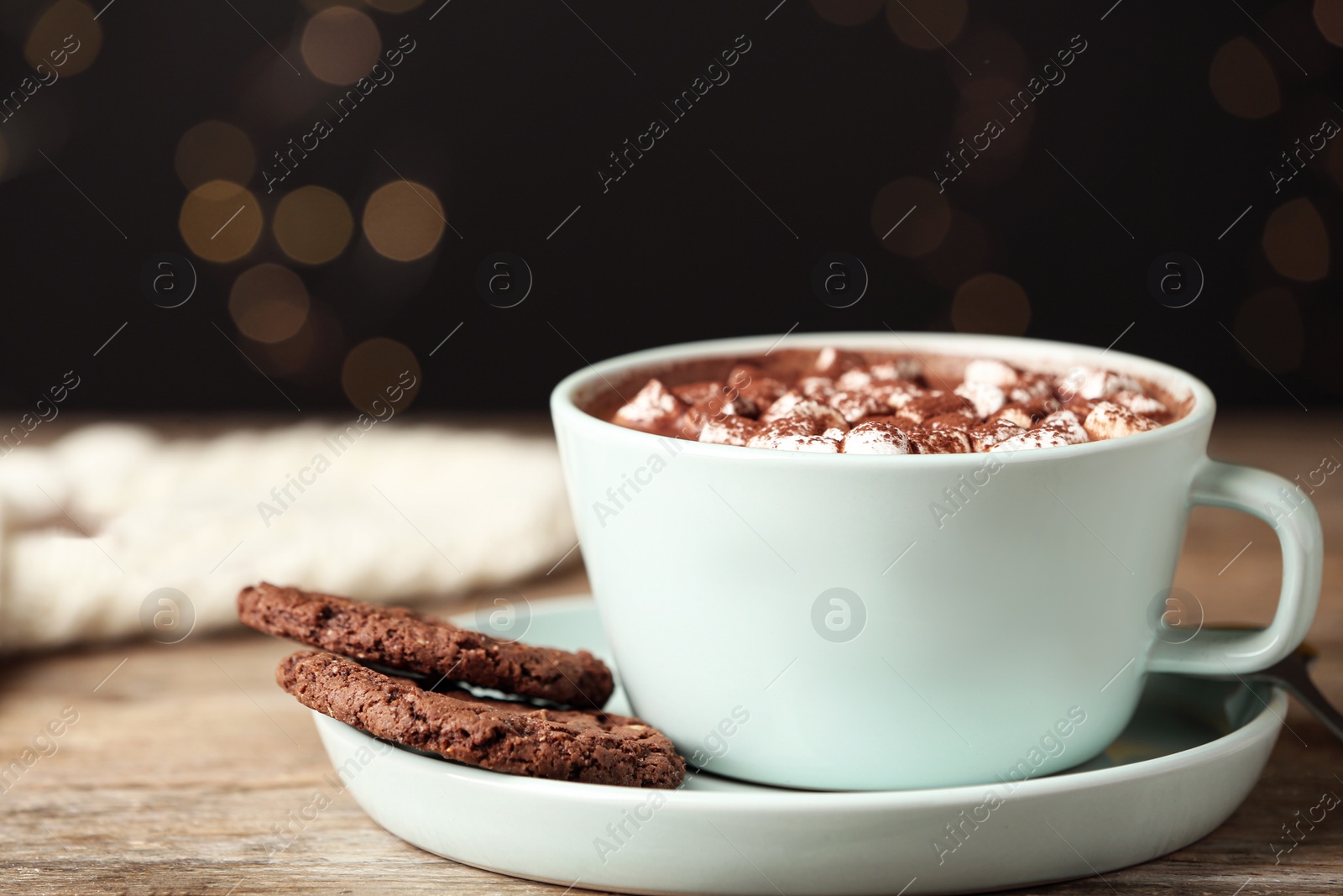 Photo of Delicious cocoa drink with marshmallows in light blue cup on wooden table