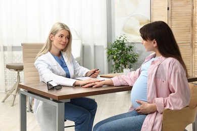 Doctor consulting pregnant patient at table in clinic