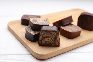 Tasty chocolate candies on white wooden table