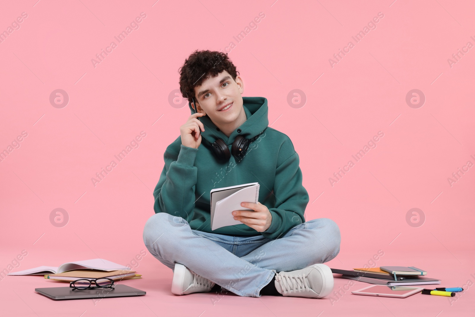 Photo of Portrait of student with notebook and stationery sitting on pink background