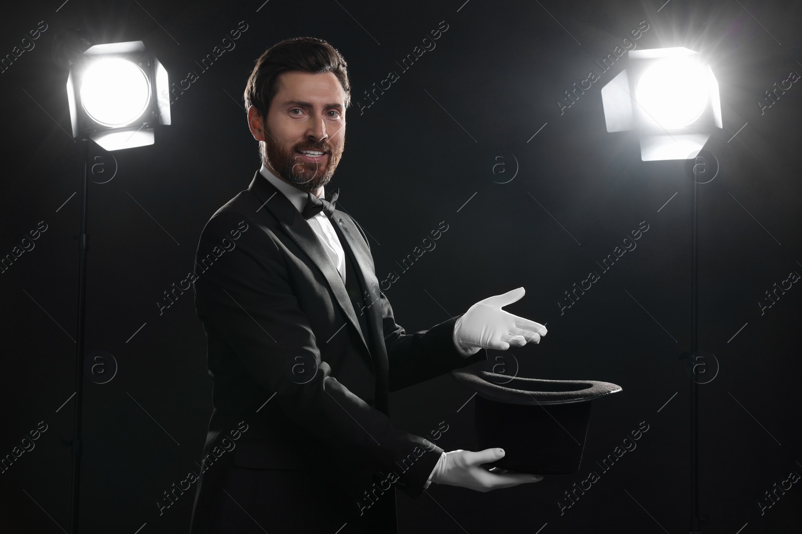 Photo of Happy magician holding top hat on stage