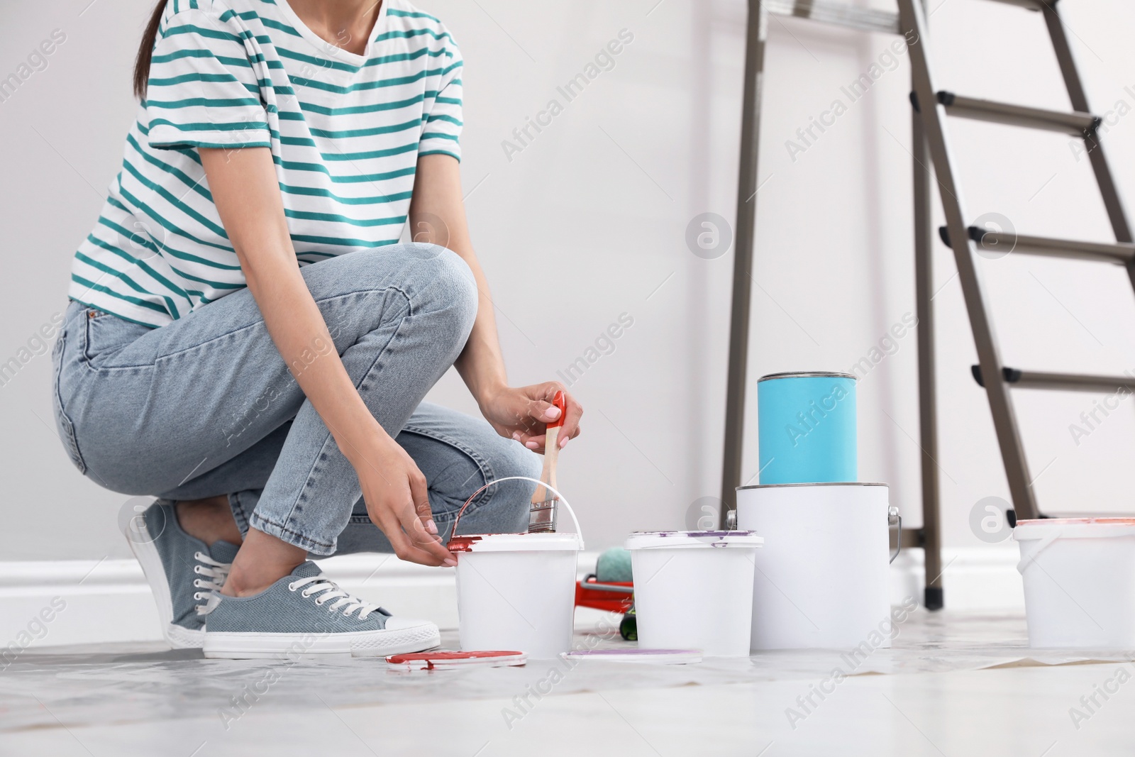 Photo of Young woman with decorator's tools near ladder indoors, closeup