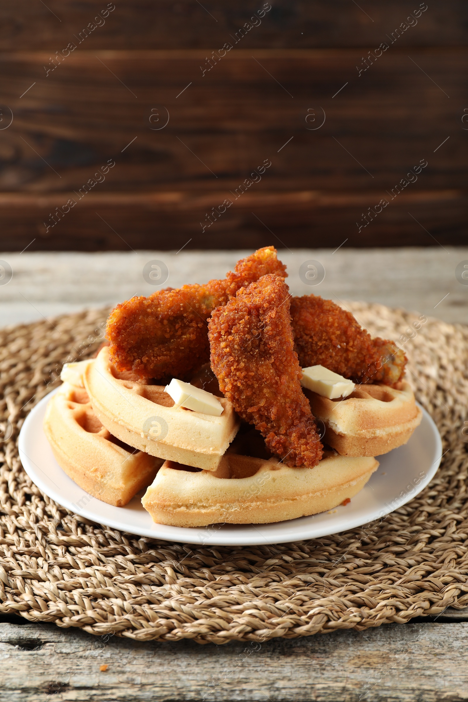 Photo of Delicious Belgium waffles served with fried chicken and butter on wooden table, closeup. Space for text