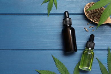Photo of Hemp oil, seeds and leaves on blue wooden table, flat lay. Space for text
