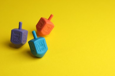 Colorful dreidels on yellow background, selective focus with space for text. Traditional Hanukkah game
