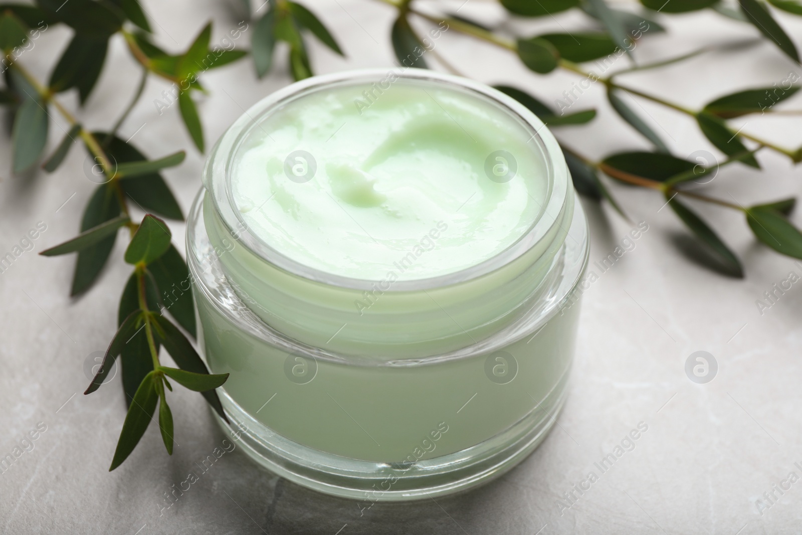 Photo of Jar of organic cream and eucalyptus on light table, closeup