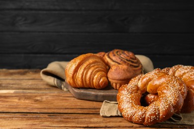 Photo of Different tasty freshly baked pastries on wooden table, space for text