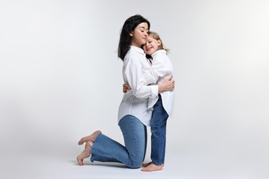 Beautiful mother with little daughter on white background