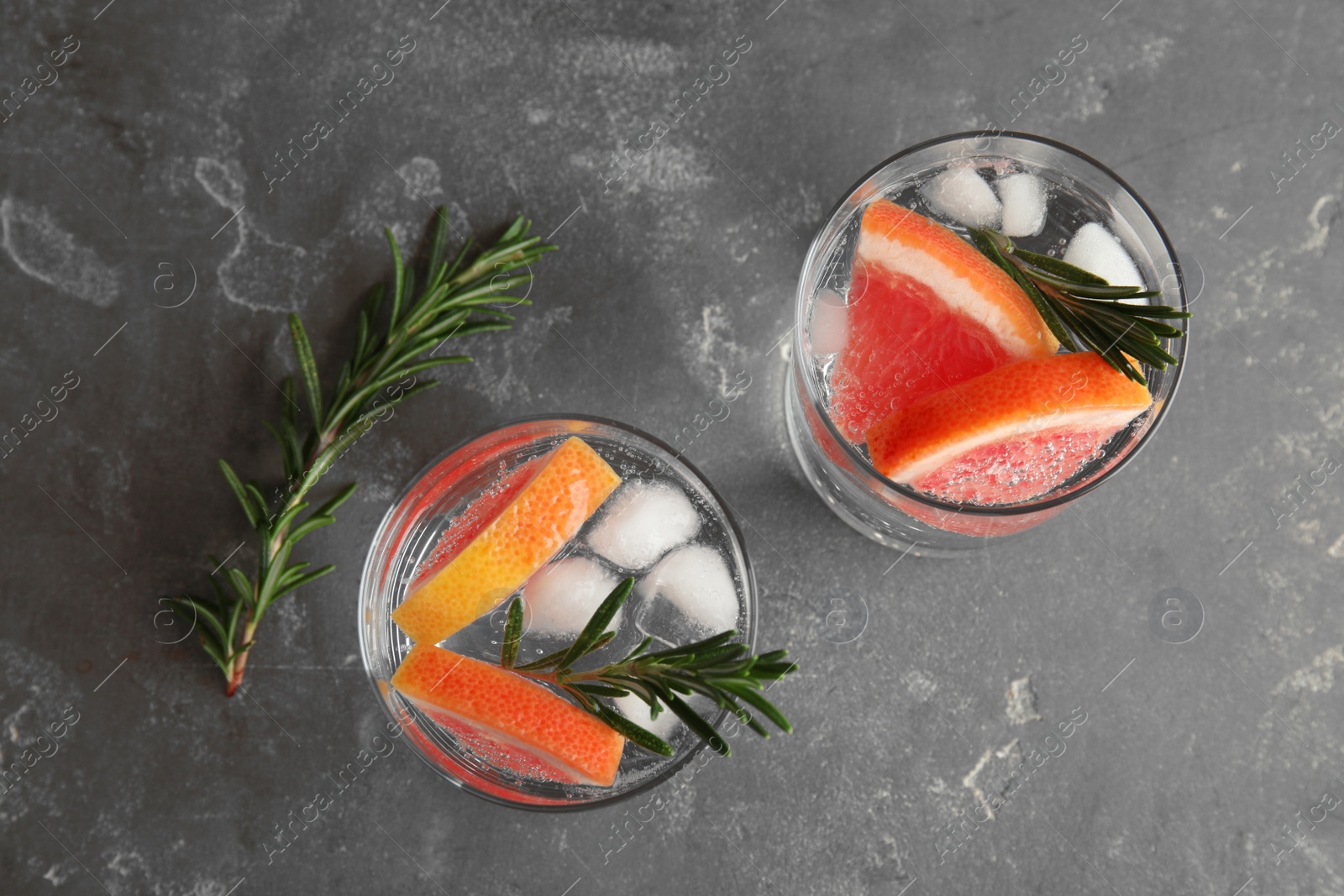 Photo of Glasses of infused water with grapefruit slices on grey table, top view