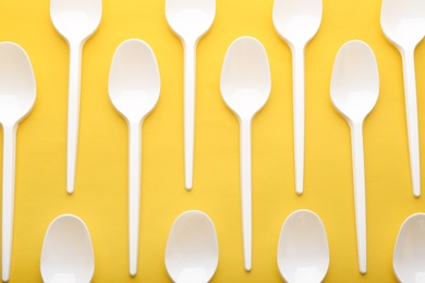 Photo of Plastic spoons on color background, top view. Picnic table setting