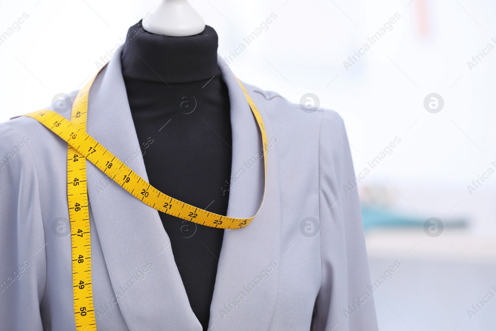 Photo of Mannequin with jacket and measuring tape in tailor studio, closeup