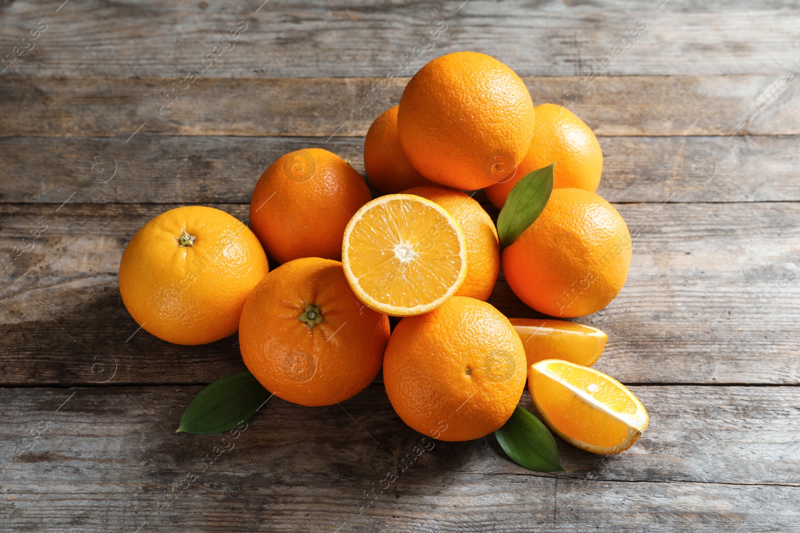 Photo of Fresh oranges with leaves on wooden background