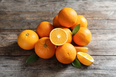 Photo of Fresh oranges with leaves on wooden background