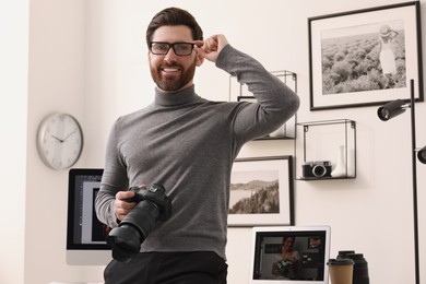 Professional photographer in glasses with digital camera in office