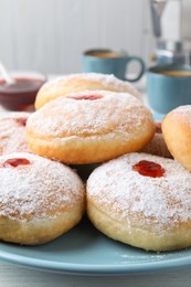 Photo of Delicious donuts with jam and powdered sugar on blue plate, closeup
