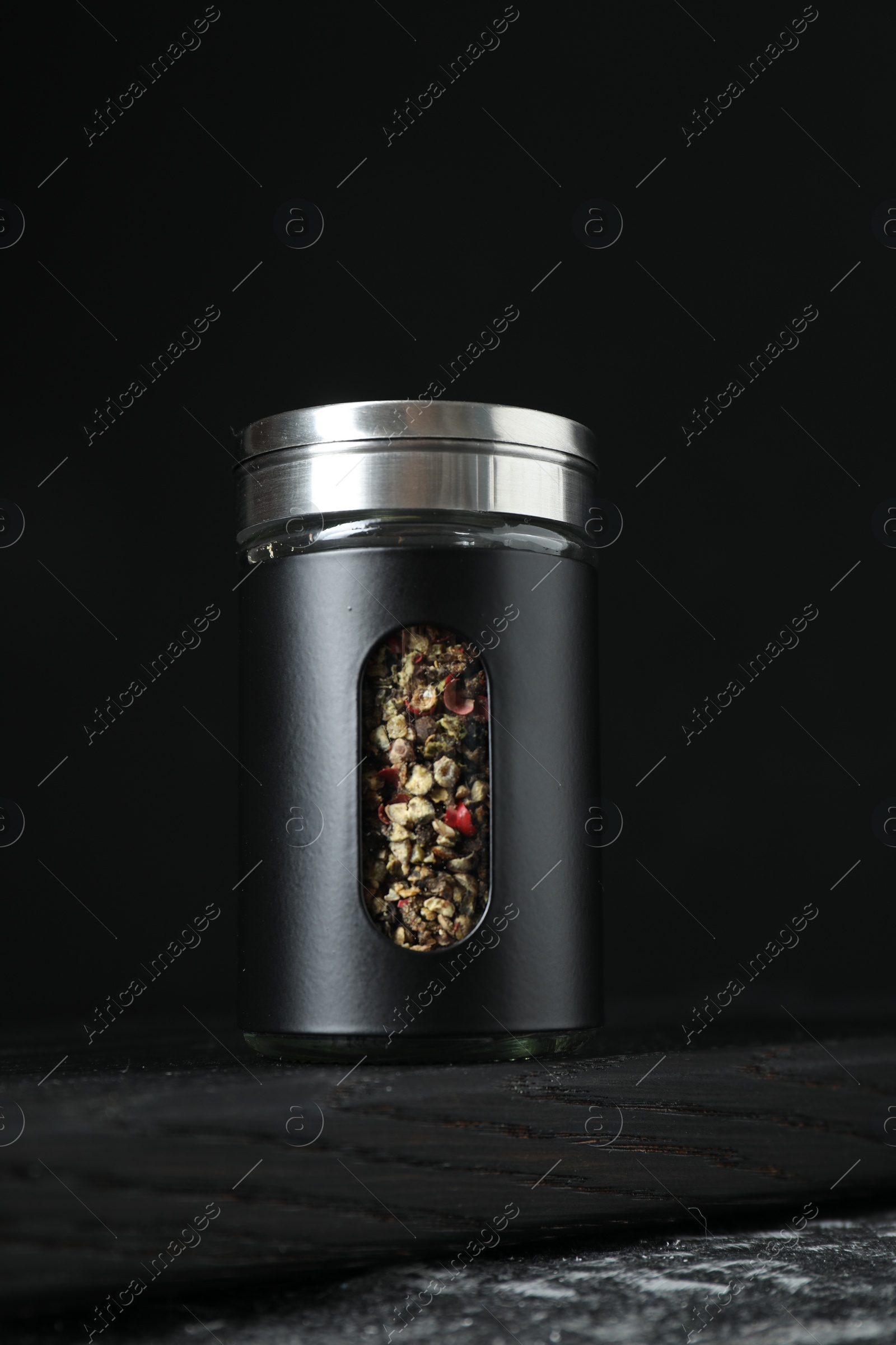 Photo of Pepper shaker on dark table against black background