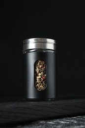 Photo of Pepper shaker on dark table against black background