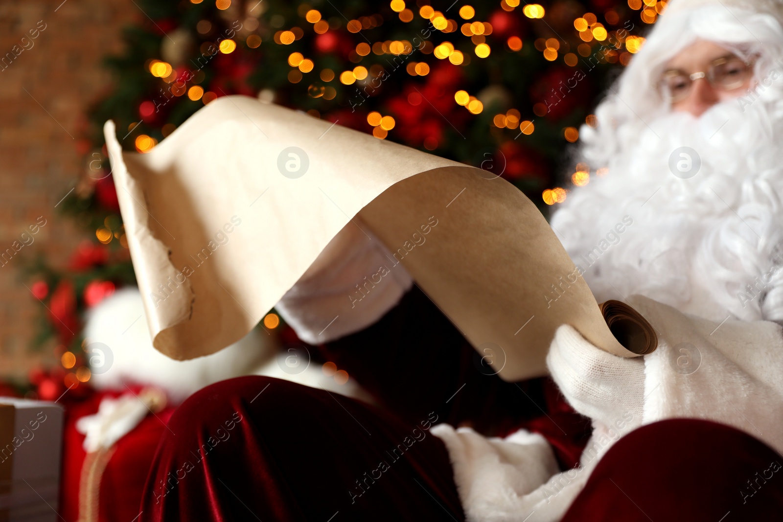 Photo of Santa Claus reading wish list against blurred festive lights, closeup