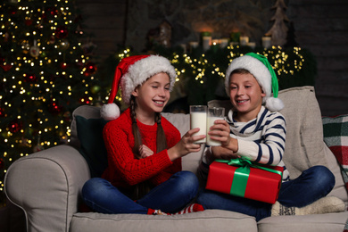 Photo of Happy children with glasses of milk at home. Christmas time