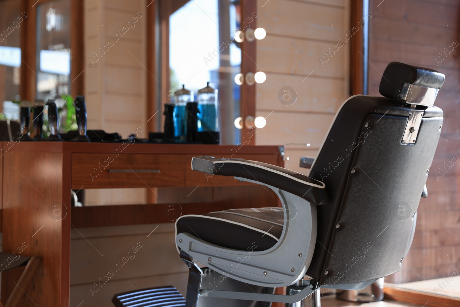 Photo of Stylish hairdresser's workplace with professional armchair and beautiful big mirror in barbershop