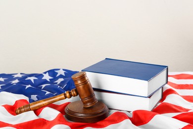 Photo of Judge's gavel and books on American flag against white background, space for text