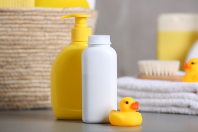 Baby cosmetic products and rubber duck on grey table