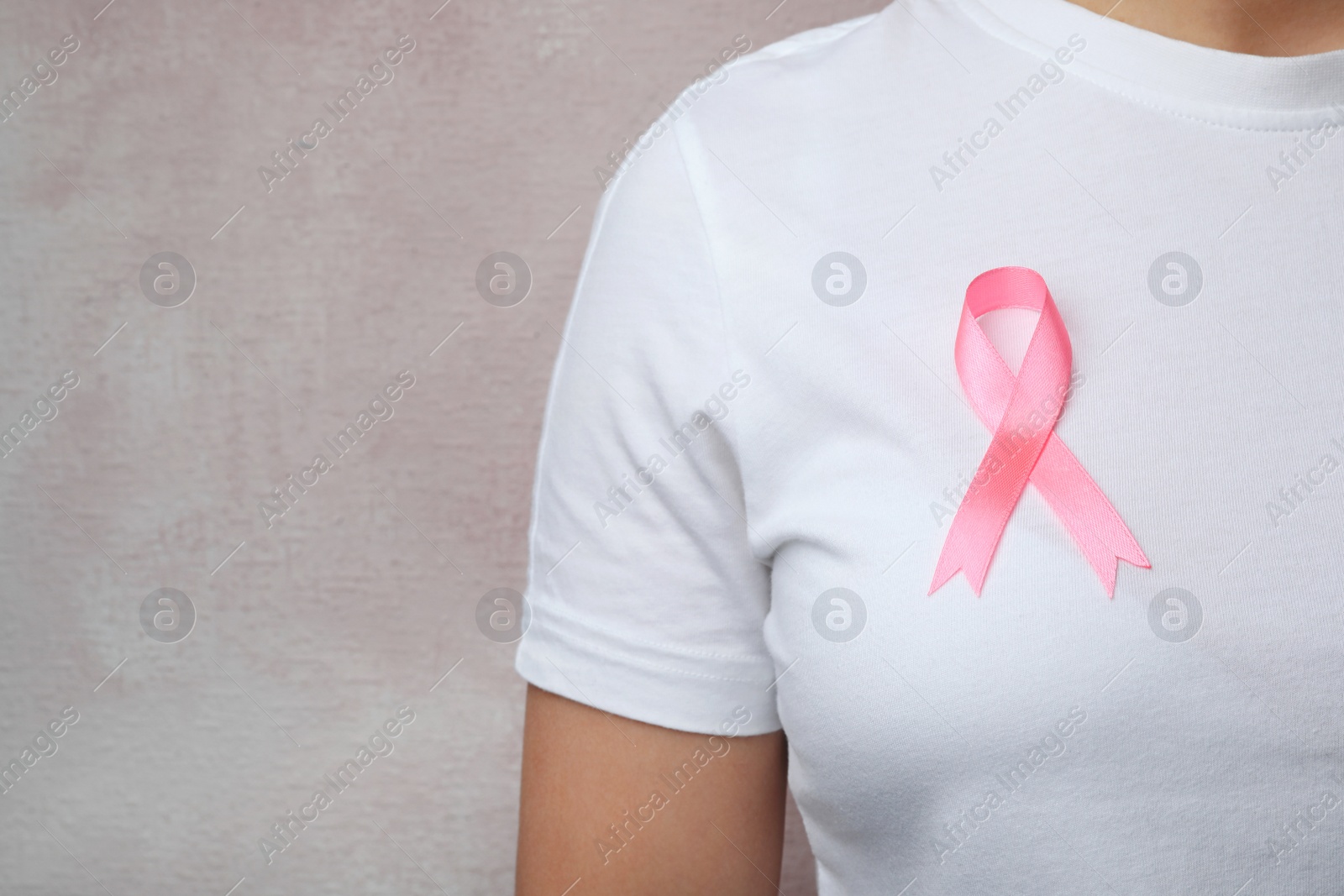 Photo of Woman with pink ribbon on color background, space for text. Breast cancer awareness