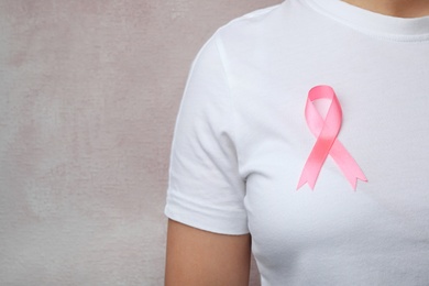 Woman with pink ribbon on color background, space for text. Breast cancer awareness