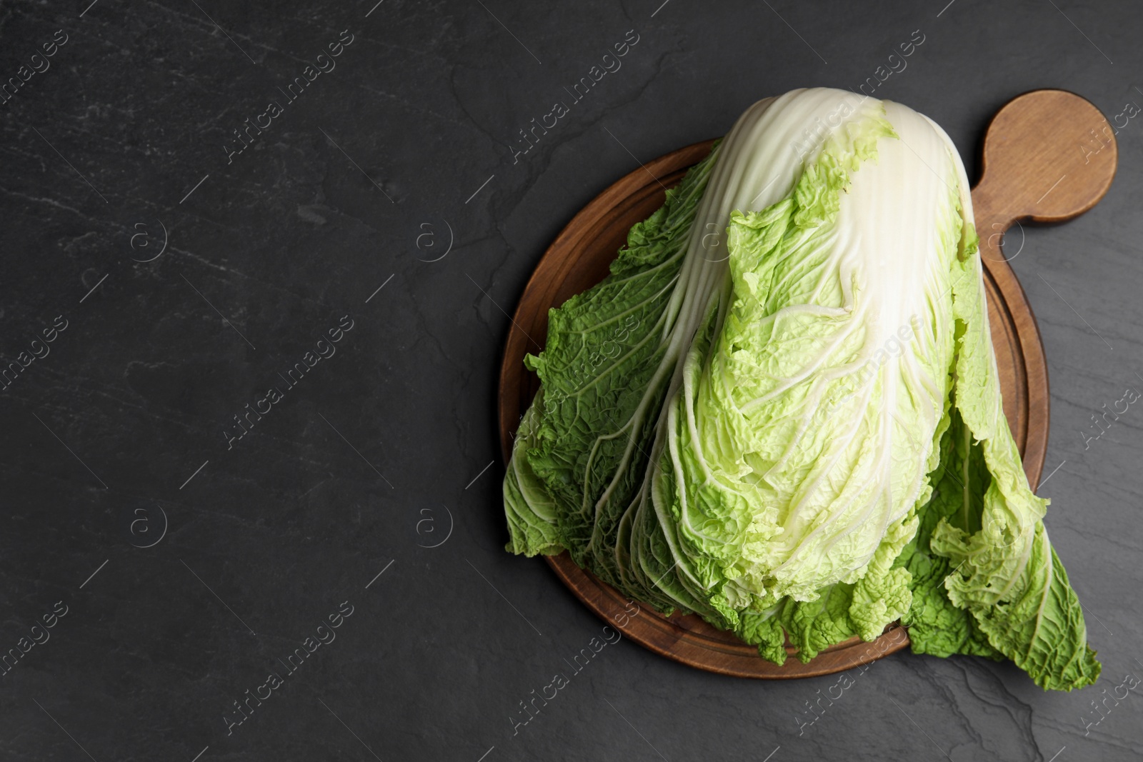 Photo of Fresh ripe Chinese cabbage on black table, top view. Space for text