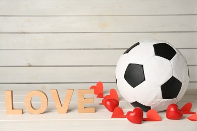 Photo of Soccer ball, hearts and word Love on white wooden table