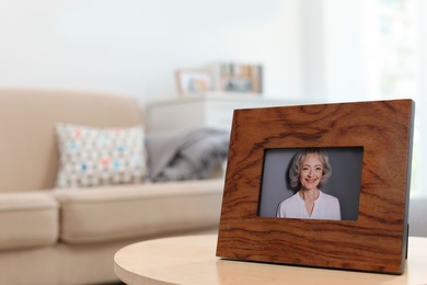 Framed portrait of senior woman on table indoors. Space for text