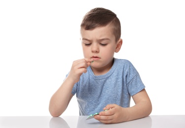 Photo of Little child taking pill on white background. Household danger