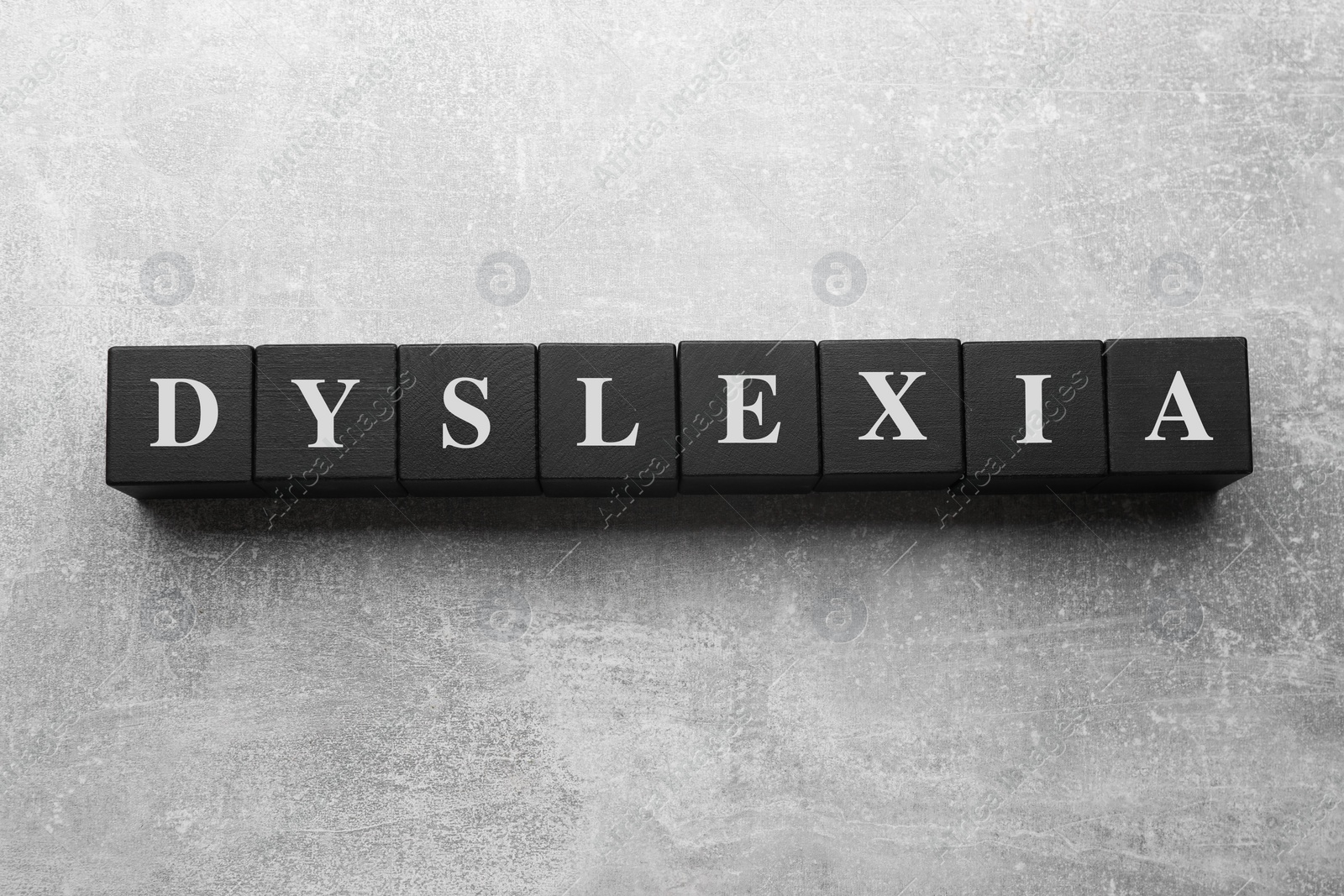 Photo of Wooden cubes with word Dyslexia on light grey stone table, flat lay