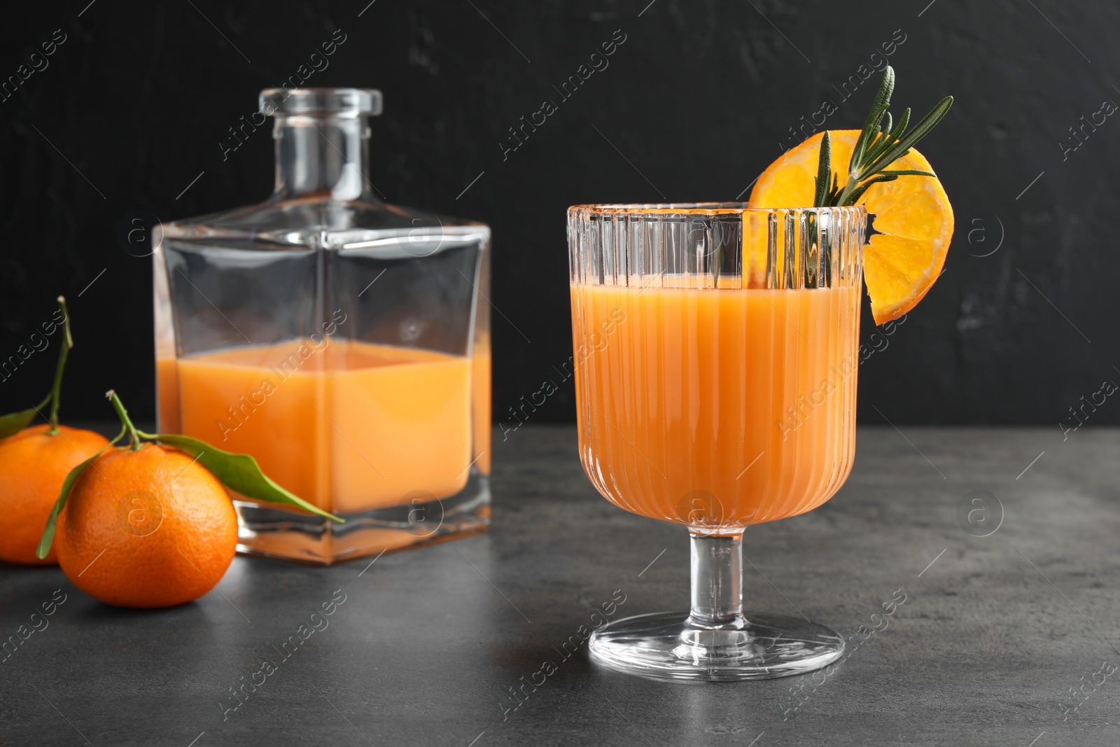 Photo of Delicious tangerine liqueur and fresh fruits on grey table