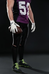 Photo of American football player with ball on dark background, closeup