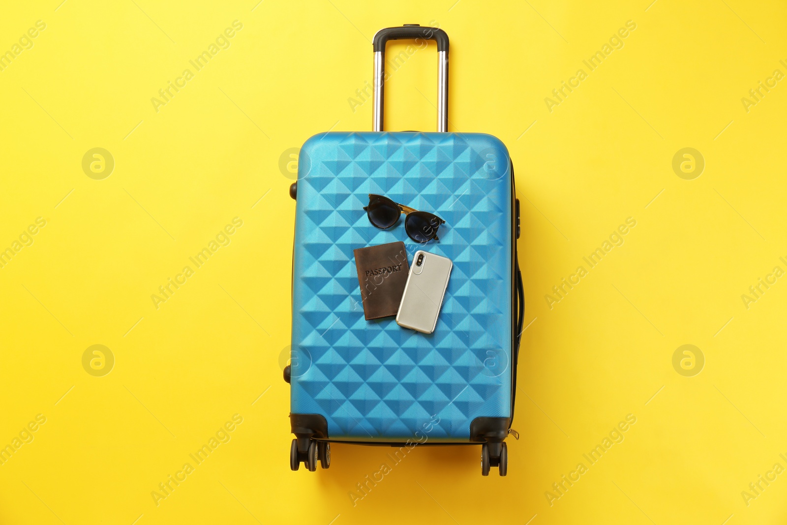 Photo of Stylish suitcase with sunglasses, smartphone and passport on color background, top view