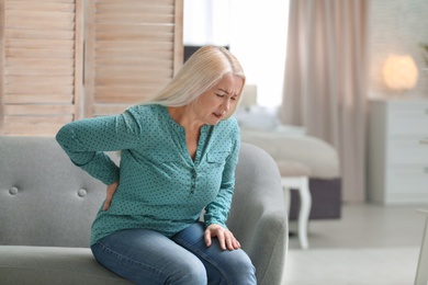 Photo of Senior woman suffering from back pain at home