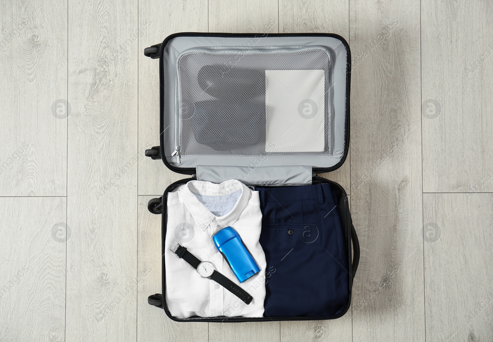 Photo of Deodorant in packed suitcase on floor, top view