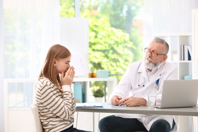 Coughing teenage girl visiting doctor at clinic