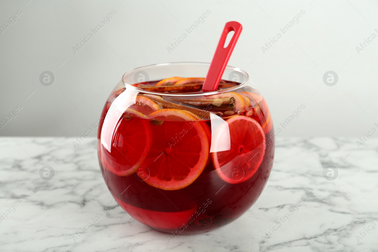 Photo of Glass bowl of aromatic punch drink on white marble table