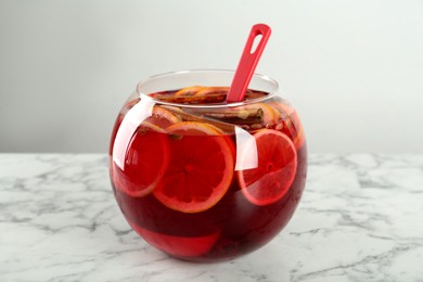 Photo of Glass bowl of aromatic punch drink on white marble table