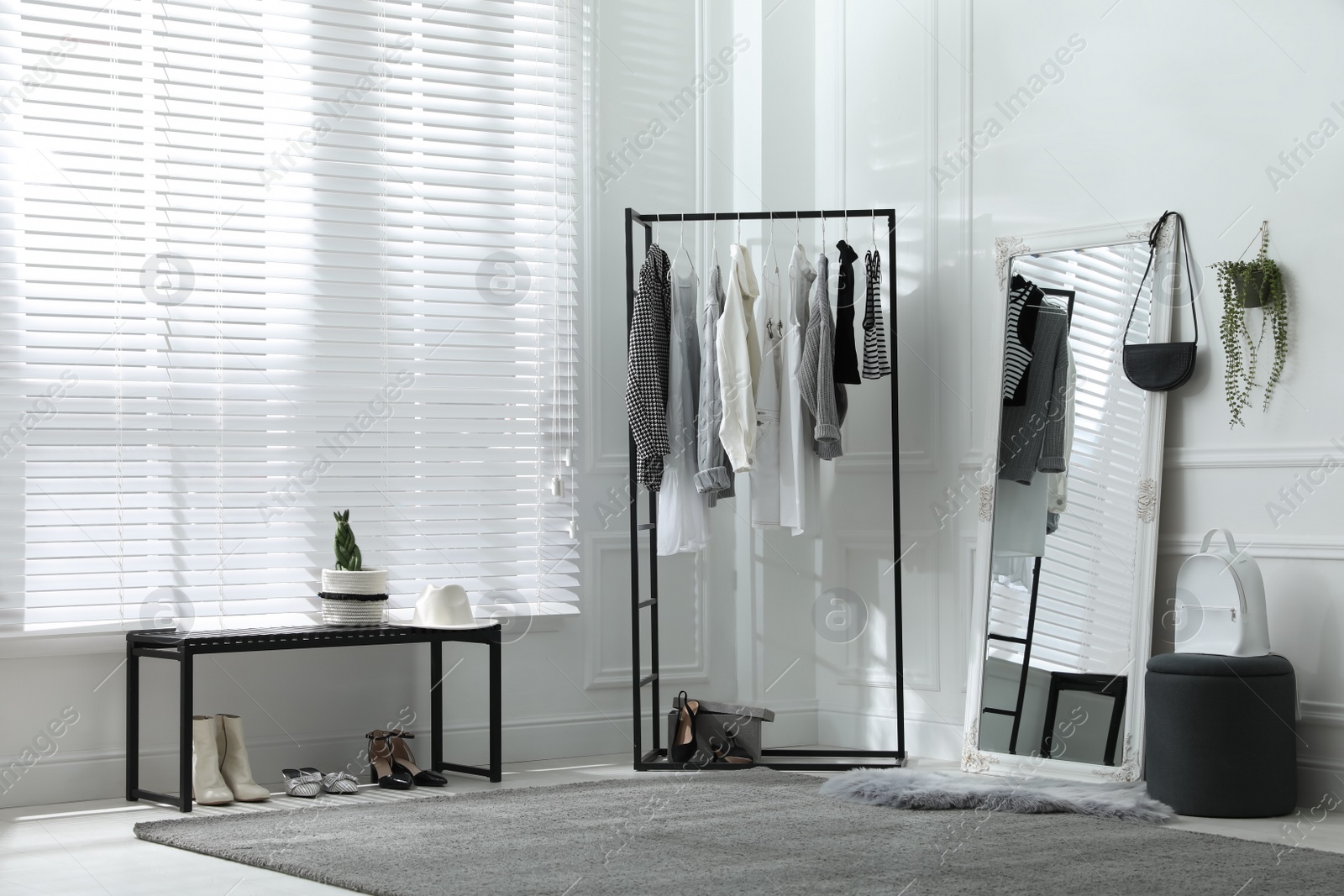 Photo of Rack with stylish women's clothes and large mirror in dressing room. Interior design