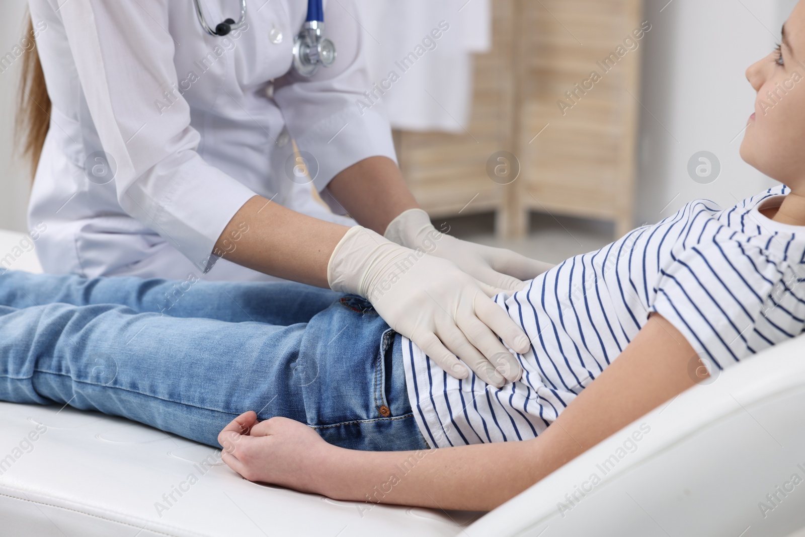 Photo of Gastroenterologist examining girl with stomach ache on couch in clinic, closeup