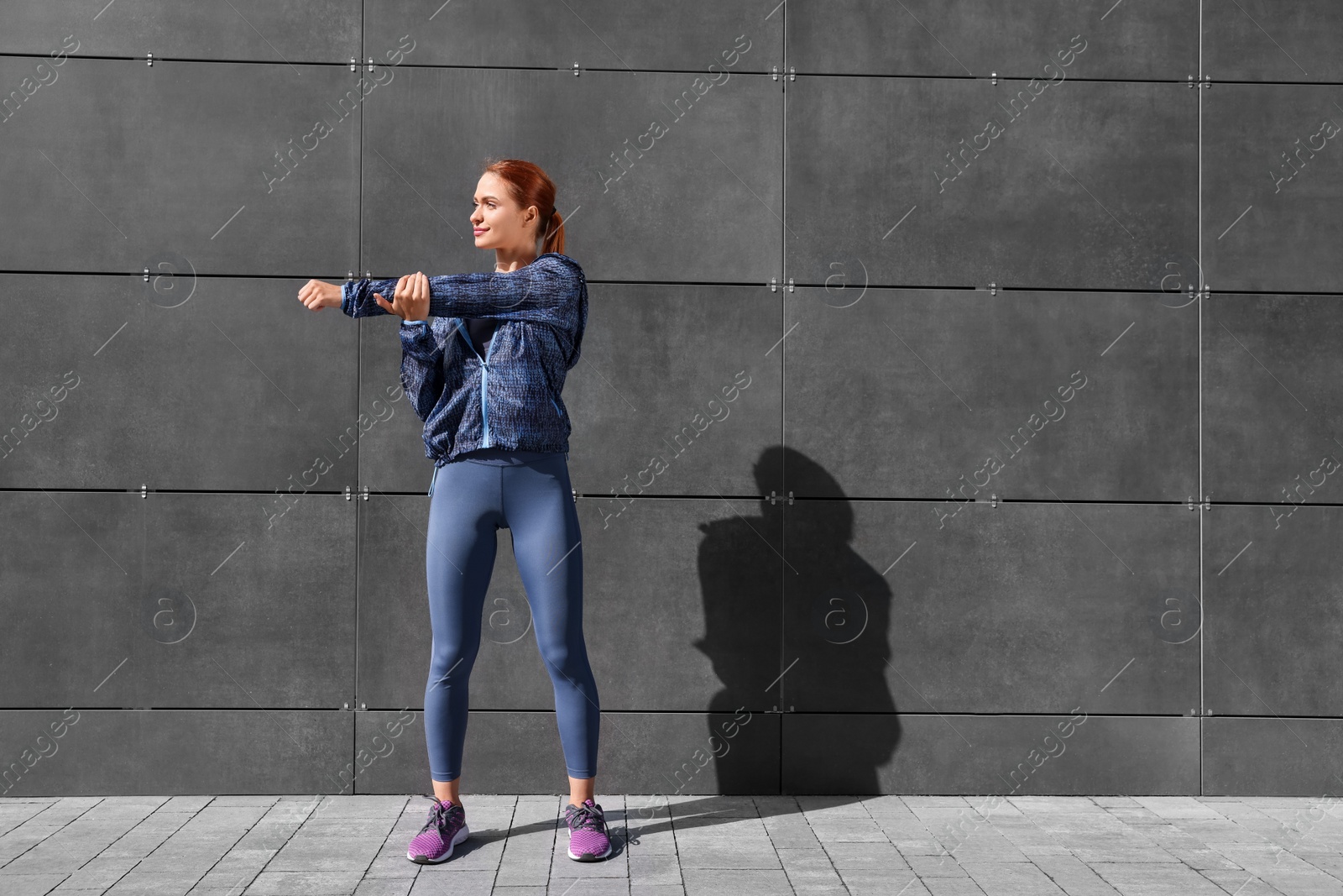 Photo of Beautiful woman in gym clothes doing exercises on street, space for text