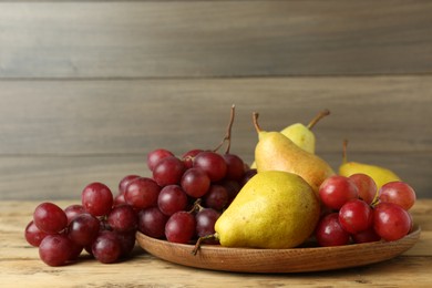 Fresh ripe pears and grapes on wooden table