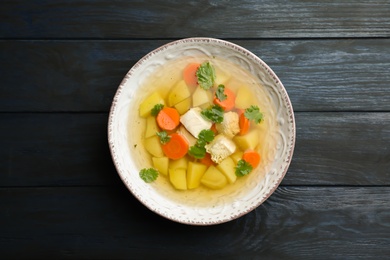 Dish with fresh homemade chicken soup on wooden  background, top view