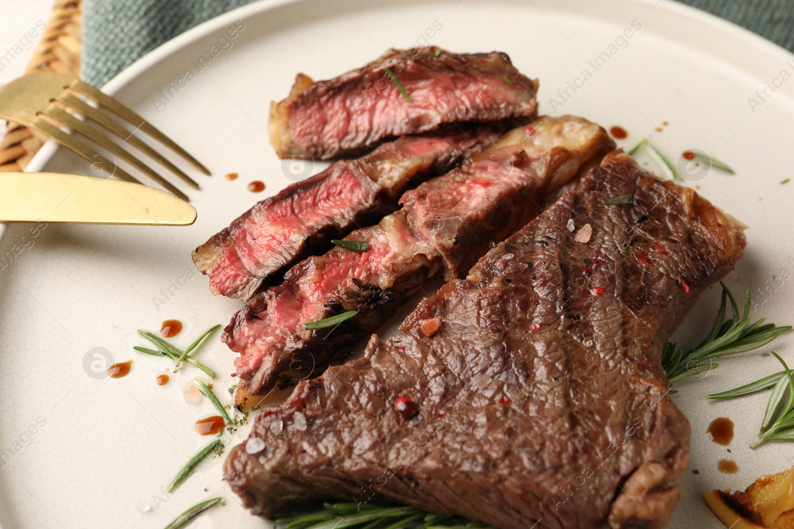 Photo of Delicious grilled beef steak and rosemary on plate, closeup