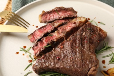 Photo of Delicious grilled beef steak and rosemary on plate, closeup